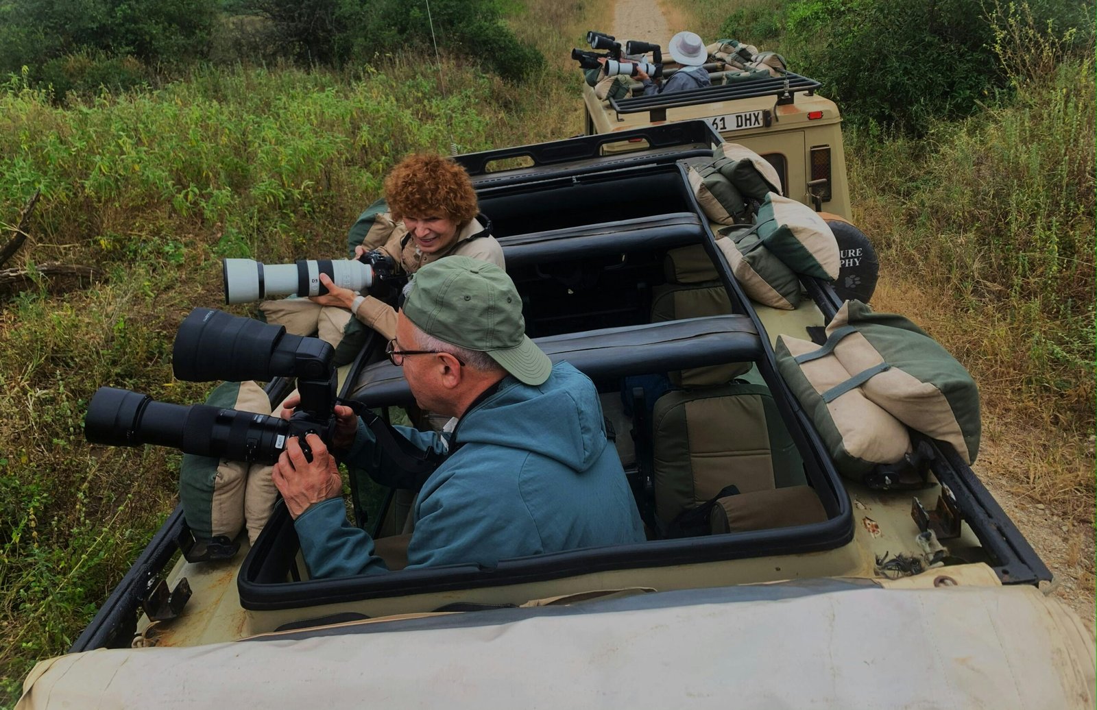 Photographers capturing wildlife from safari vehicles in a wilderness setting.