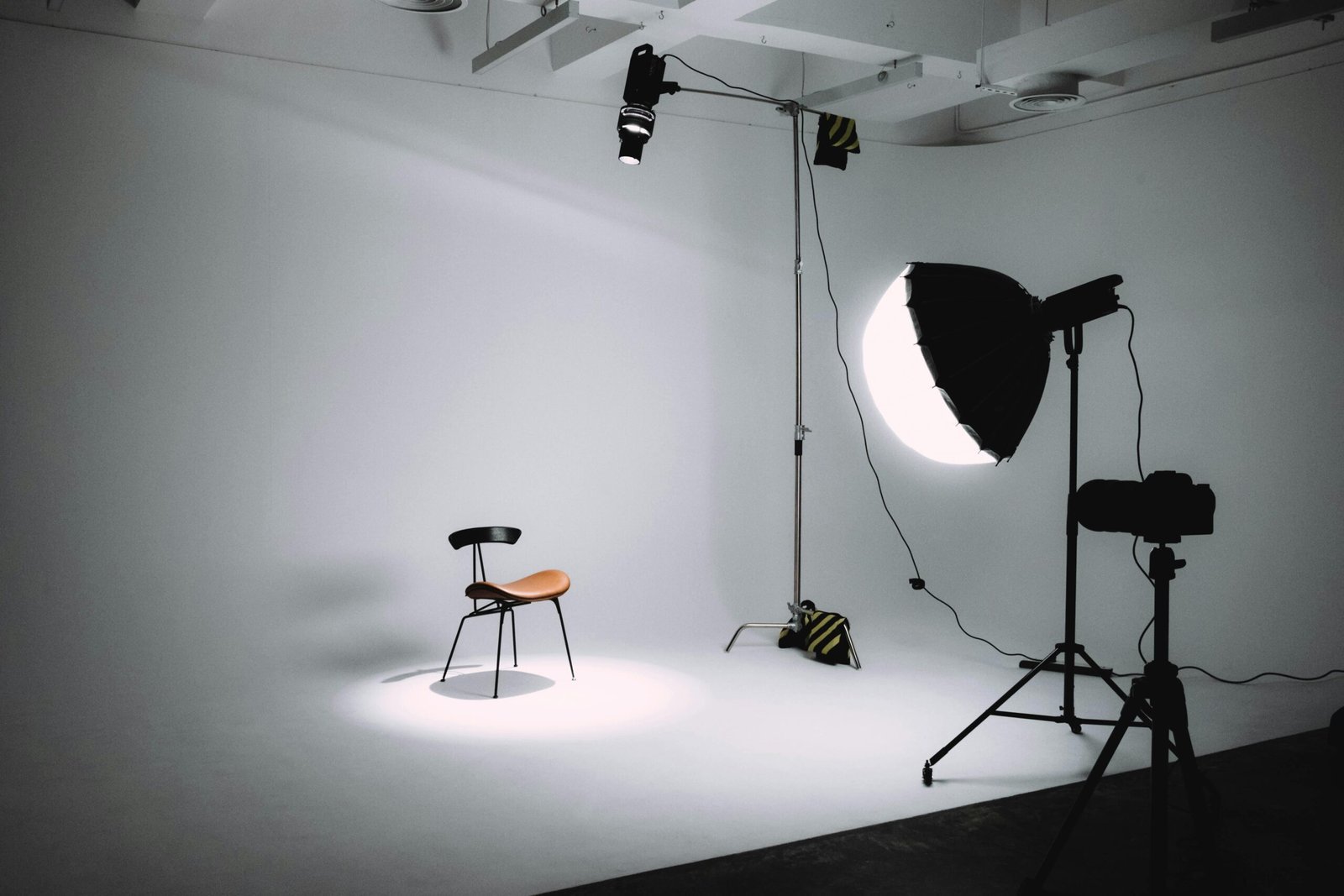 Empty photography studio with lighting equipment focused on a single chair.