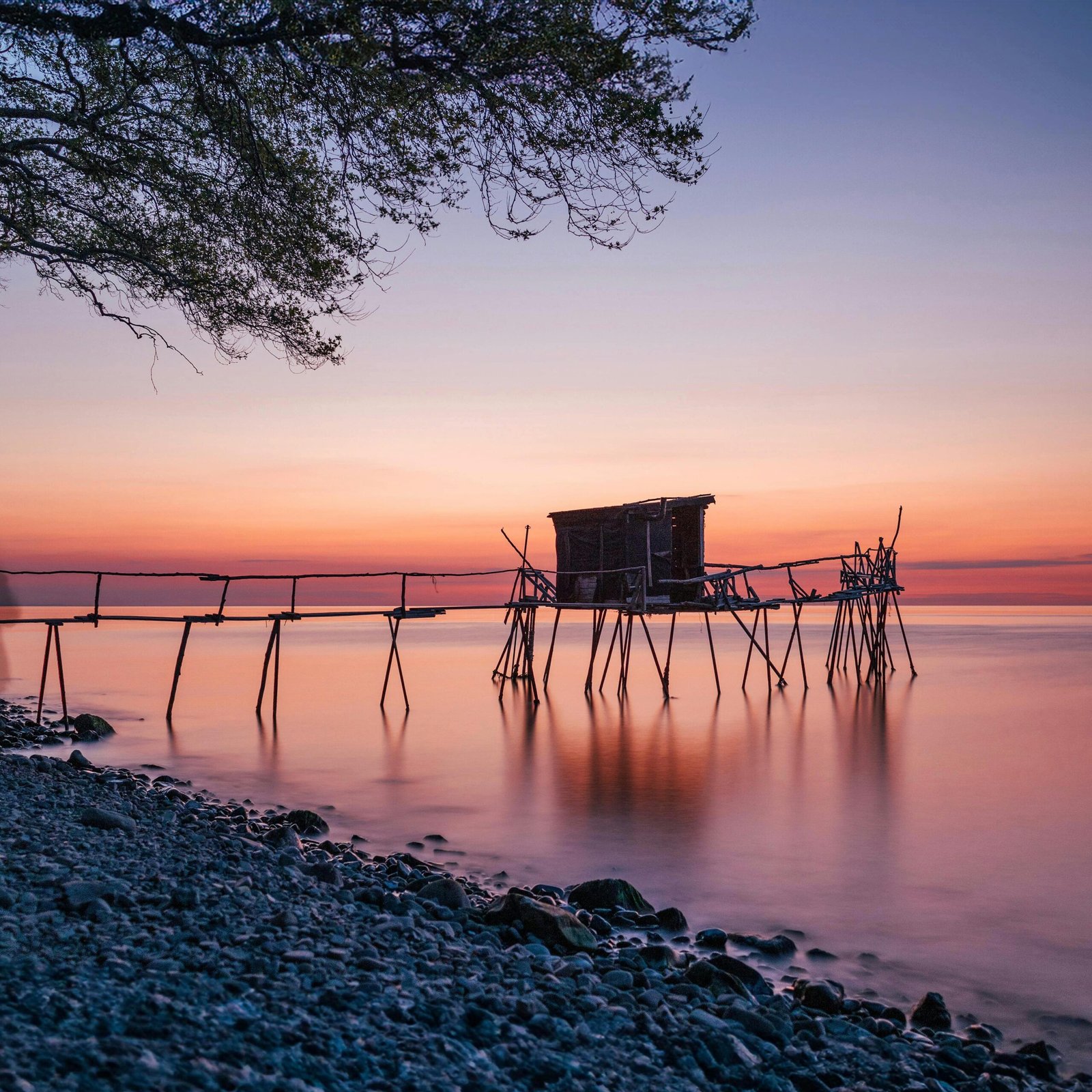 Tranquil sunrise view of a rustic fishing pier in Tekirdağ, Türkiye, with calm seas and colorful sky.